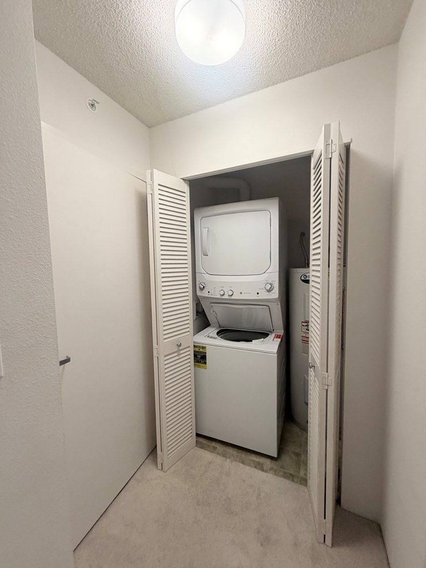 A small white washing machine is in a small room.